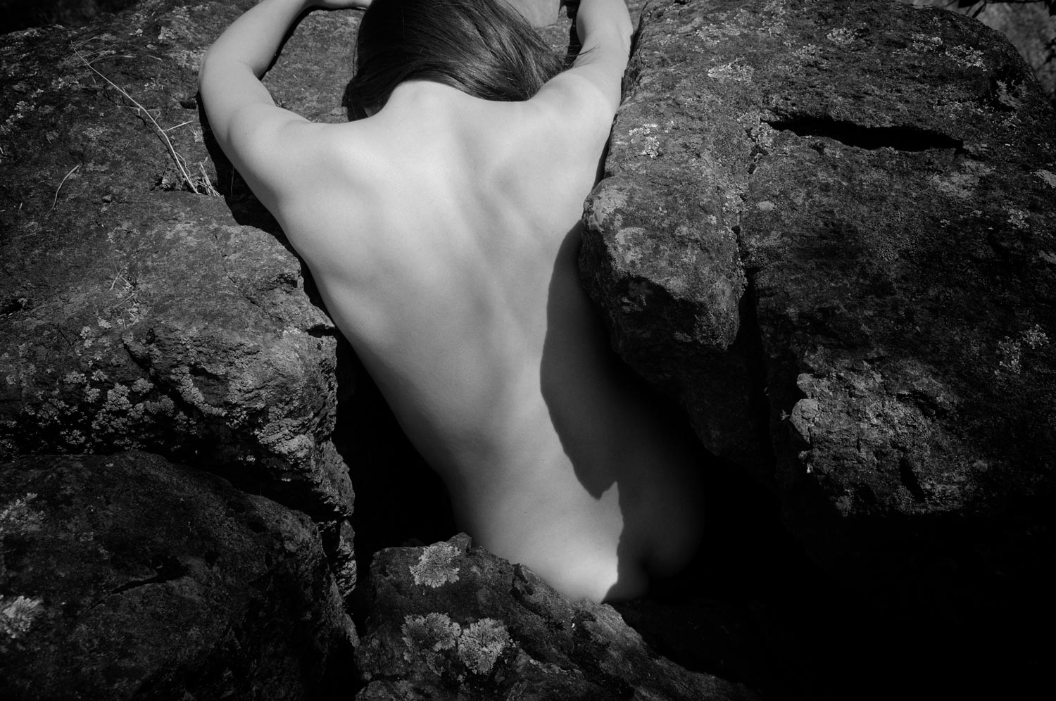 The dancer's back fills a narrow opening between two rocks